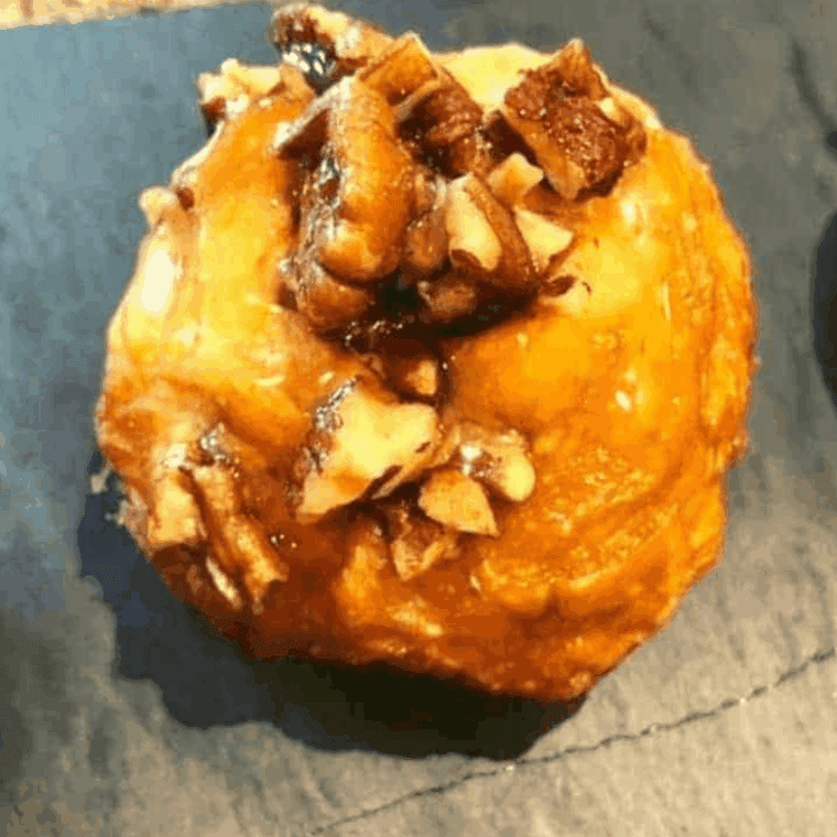 Golden brown air fryer pecan rolls topped with caramelized pecans on a white plate.