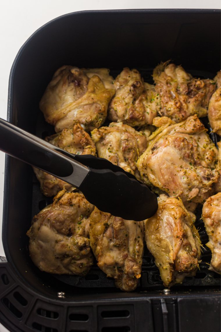 Pesto-coated chicken thighs arranged skin side up in a single layer in an air fryer basket