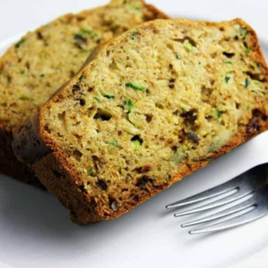 Two slices of air fryer zucchini bread on a white plate with a fork