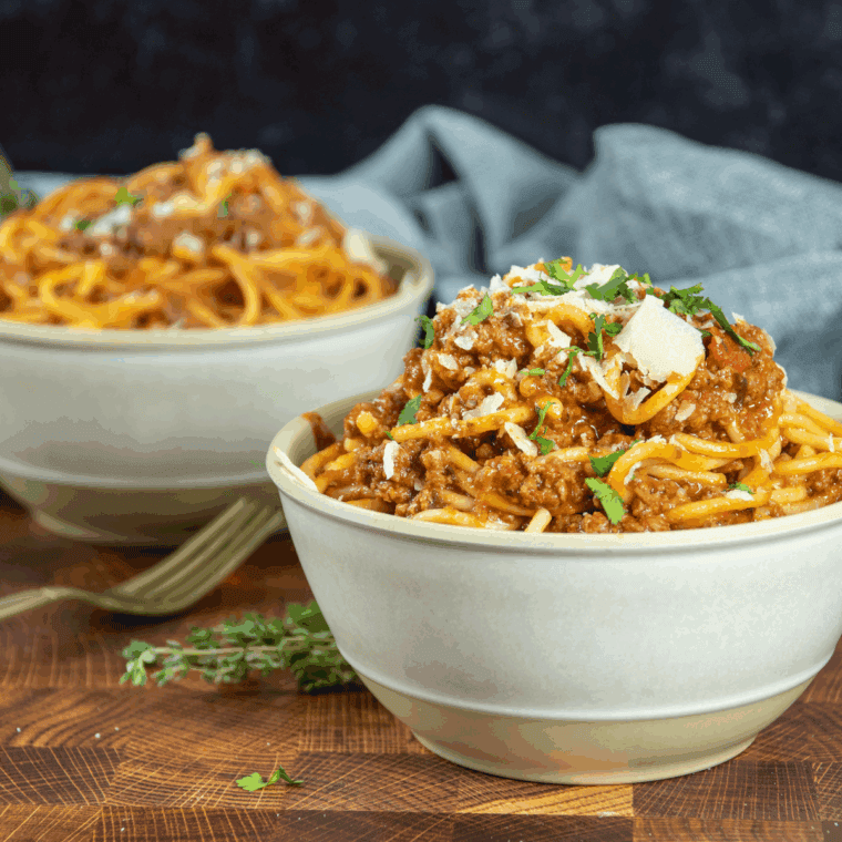 Plate of Carrabba's Spaghetti topped with meat sauce and fresh herbs.