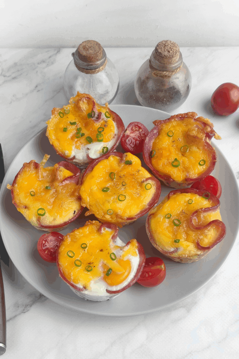 Air fryer ham and egg cups cooked in muffin molds, golden eggs baked inside ham slices for an easy breakfast.
