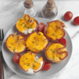 Air fryer ham and egg cups baked in a muffin-style shape with melted cheese on top
