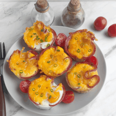 Air fryer ham and egg cups baked in a muffin-style shape with melted cheese on top