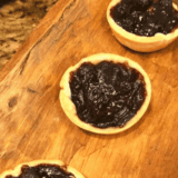 Golden air fryer jam tarts filled with bright fruit jam, served on a cooling rack.
