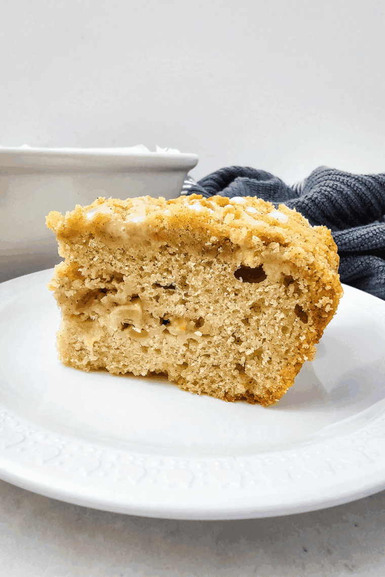 Slice of Air Fryer Apple Coffee Cake showing tender apple pieces and crumb topping, drizzled with glaze.