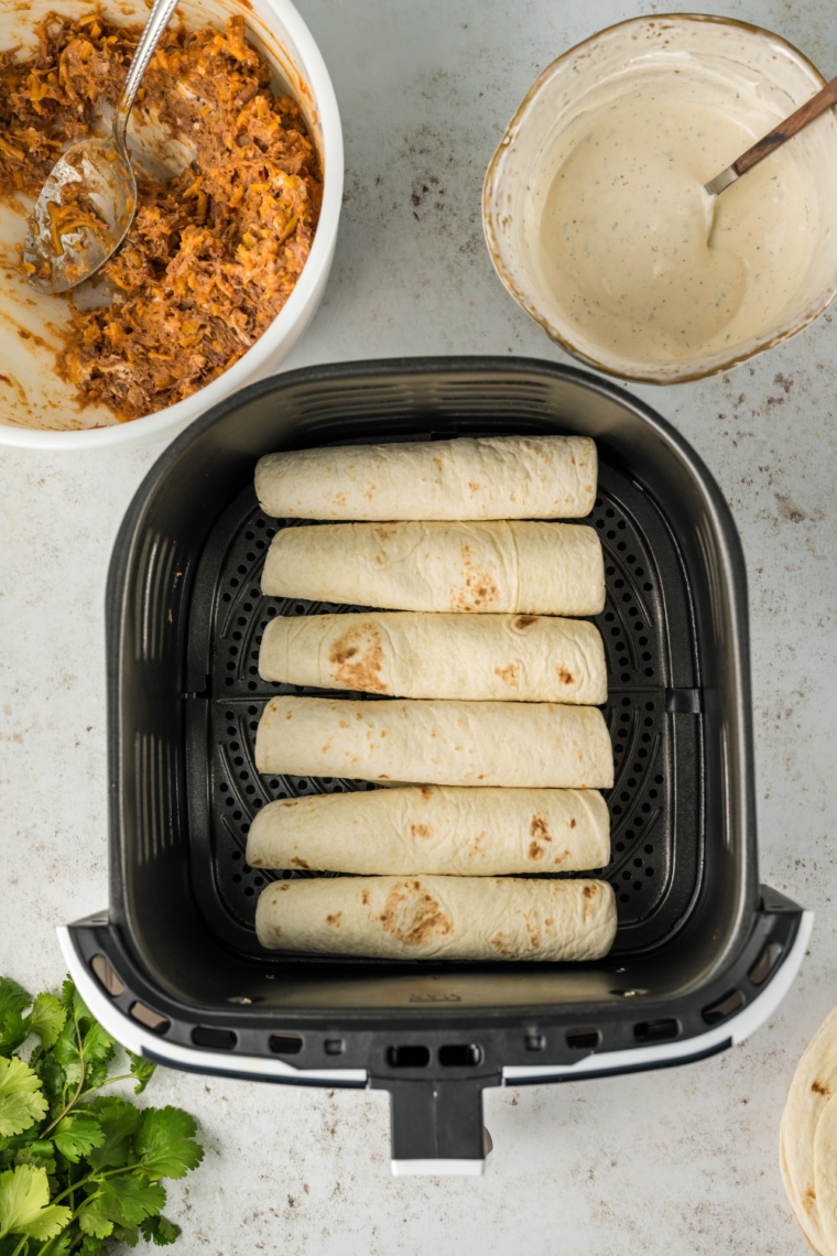 Filling and tightly rolling tortillas with beef mixture for air fryer taquitos