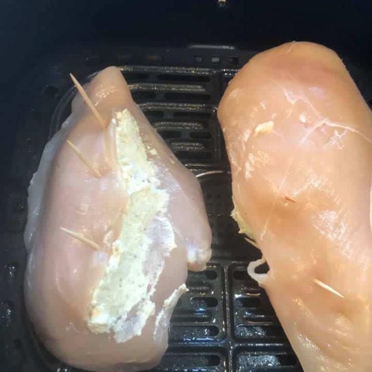 "Placing stuffed chicken breasts into the air fryer basket for cooking."