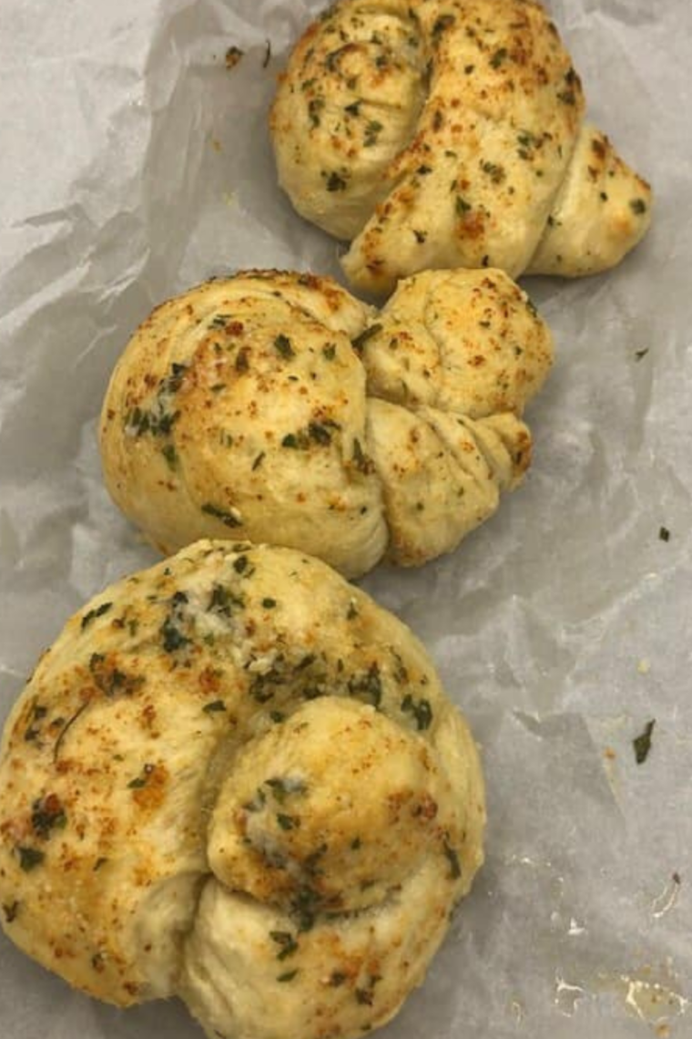 Air fryer basket filled with evenly spaced garlic knots cooking until golden brown.