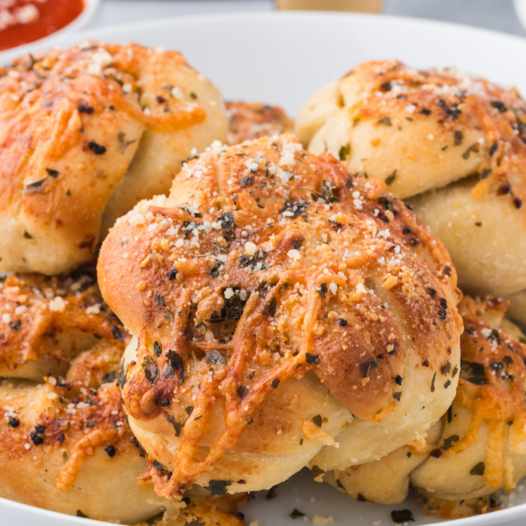 Close-up of freshly air-fried garlic knots inside a basket, lightly browned and glistening with butter.