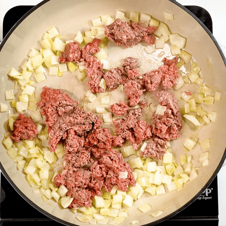 Skillet cooking with olive oil, diced onions, ground beef, and seasoning until browned and fully cooked.