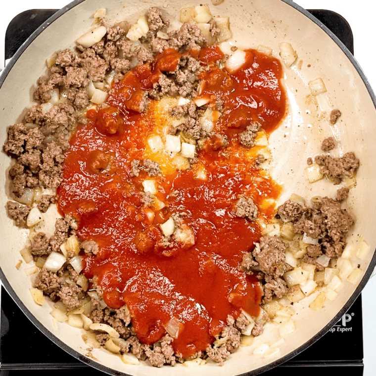 Stirring in tomato sauce and Italian seasoning, simmering to thicken.