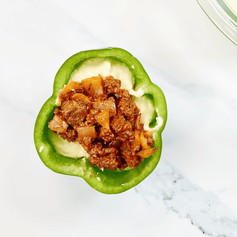 Adding ricotta mixture and topping with meat sauce in bell peppers.