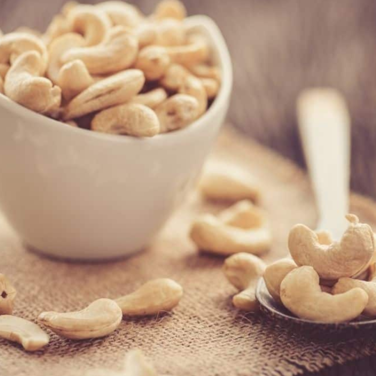 Ingredients for bbq roasted cashews on  a wooden table, with a spoon next to it.