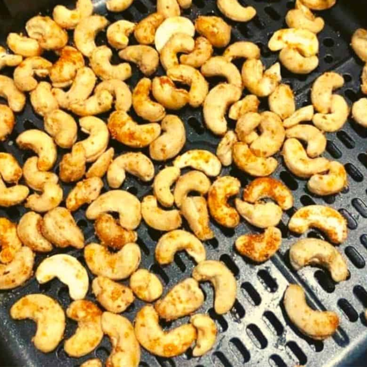 Image of seasoned cashews in the air fryer basket: "Seasoned cashews placed in the air fryer basket"