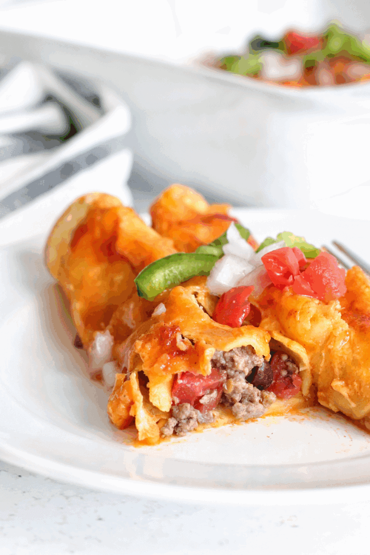 Air fryer enchiladas filled with seasoned ground beef, topped with melted cheese and sauce.