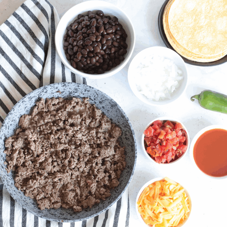 Ground beef browning in a skillet with salt, pepper, and garlic powder.