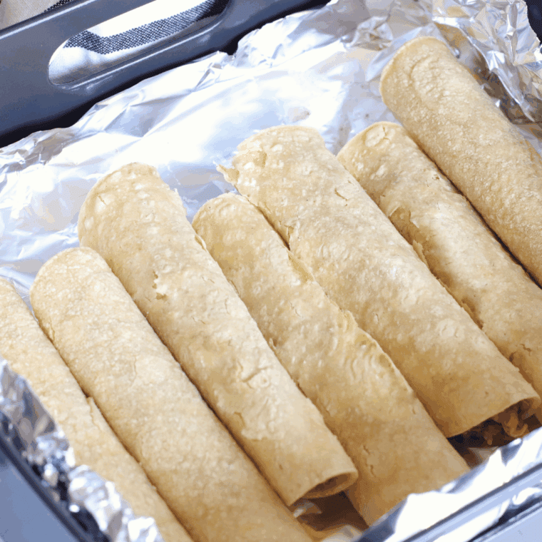 Enchiladas topped with cheese and sauce, ready to air fry until golden.