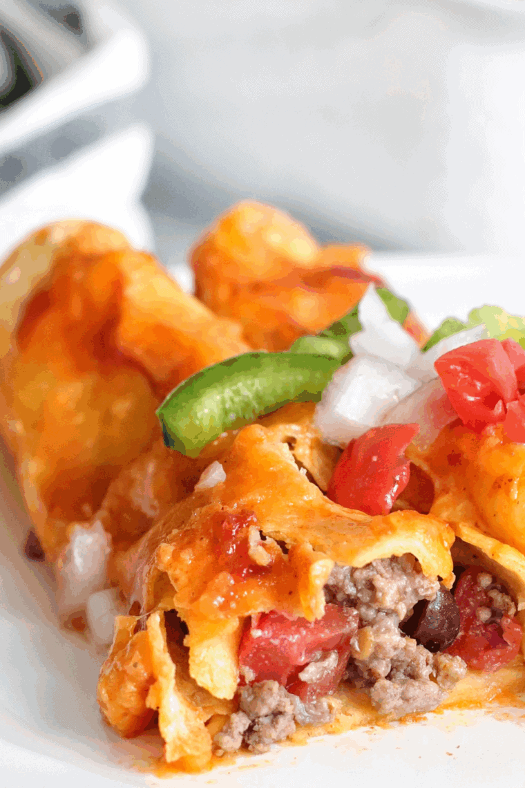 Air fryer enchiladas filled with seasoned ground beef, topped with melted cheese and enchilada sauce.