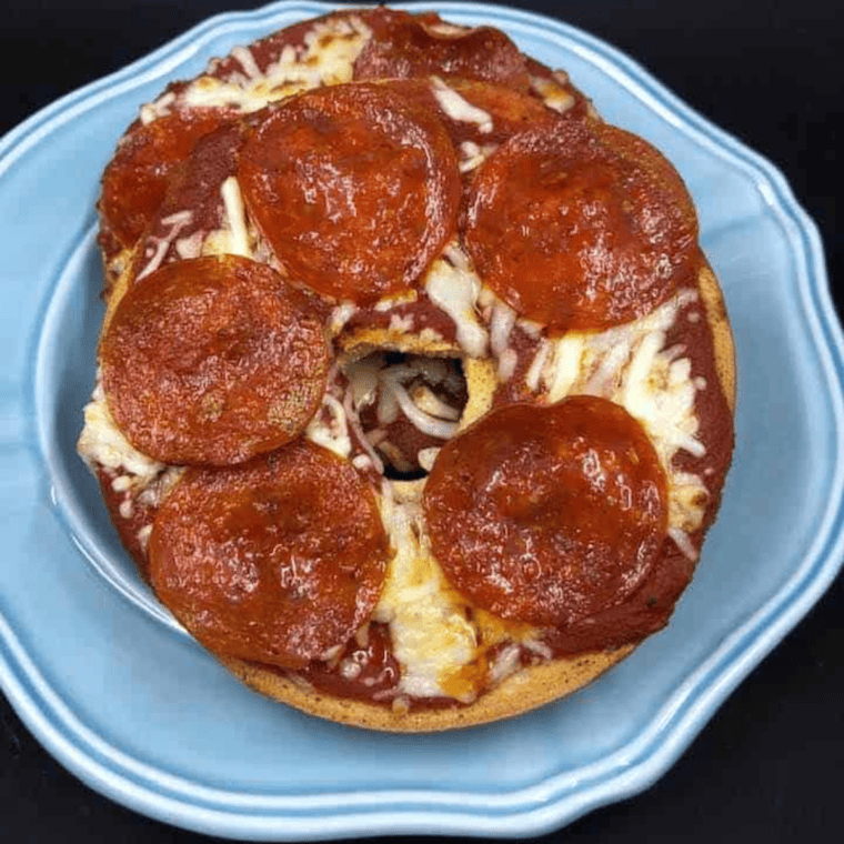 overhead closeup: pizza bagels in air fryer with cheese and pepperoni on top