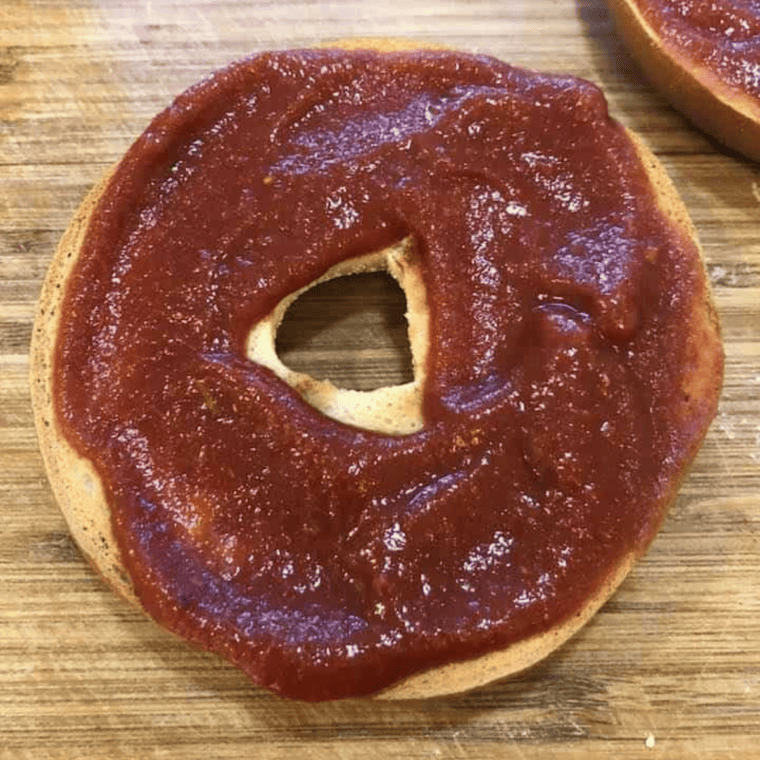 overhead process shot: sauce added to bagel for pizza bagels