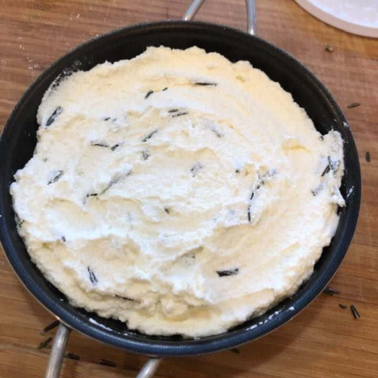 Mixing whole-milk ricotta, eggs, Parmesan cheese, minced rosemary, and lemon zest in a mixing bowl for baked ricotta.