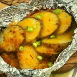 Air Fryer Cheesy Potatoes Foil Packet opened and showing the reader the melted cheese on the potatoes.