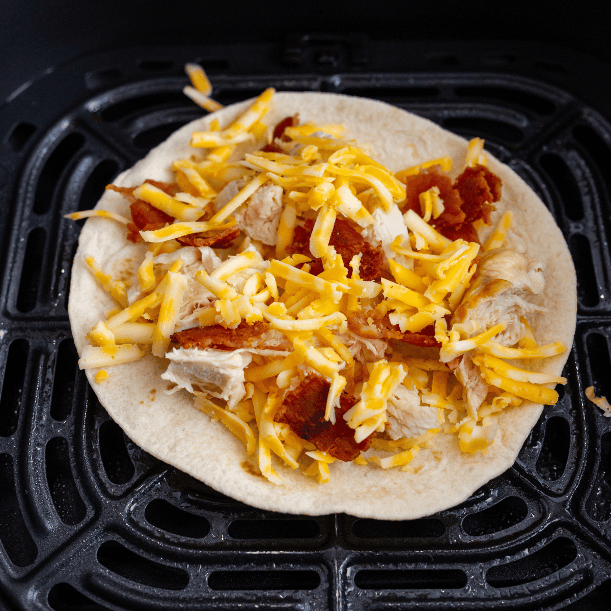 Place the flour tortilla in the air fryer basket and add the chicken and any other toppings.