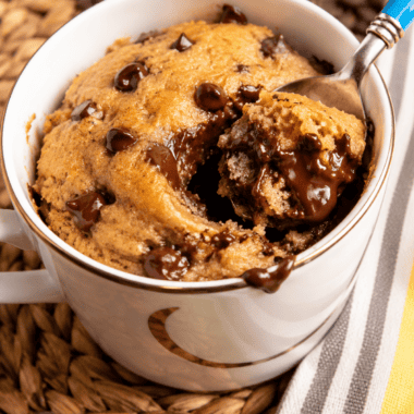 Air fryer chocolate chip mug cake baking in the basket until golden