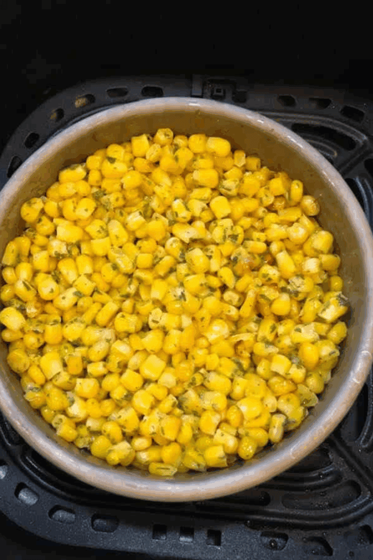 Corn cooking in the air fryer at 400°F for 3 minutes, ready to be stirred before cooking for another 3 minutes.