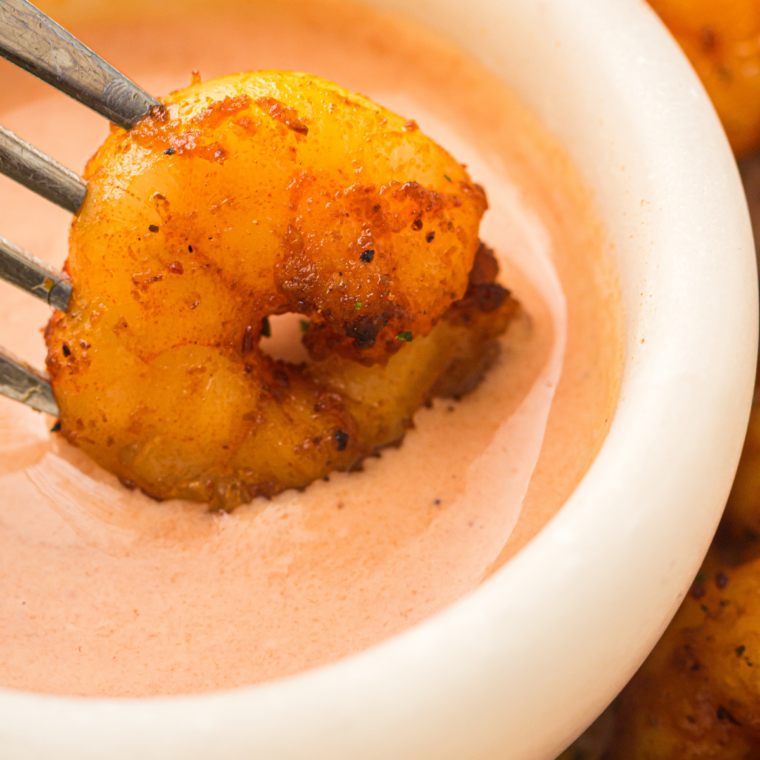 Plate of golden air fryer lemon garlic shrimp garnished with fresh parsley and lemon wedges