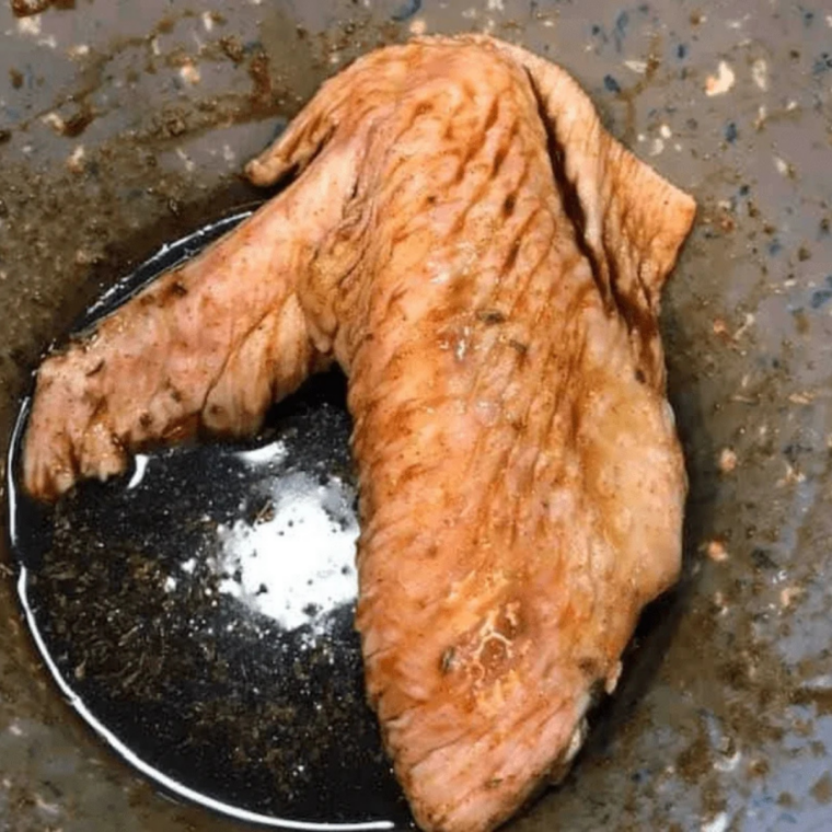 turkey wings being coated in olive oil and seasoning blend in a mixing bowl