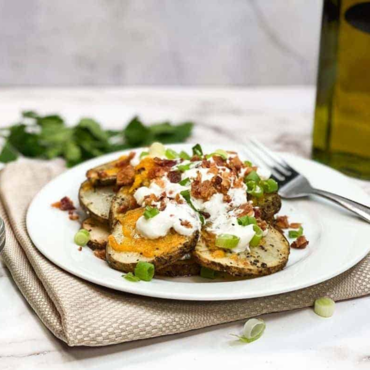 Plate of Air Fryer Loaded Baked Potato Foil Packs featuring crispy, golden potatoes topped with melted cheese, crispy bacon bits, and fresh chives.