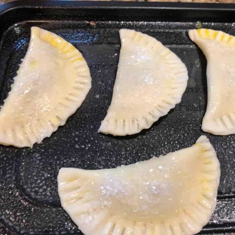 Placing the filled hand pies in the air fryer basket before cooking