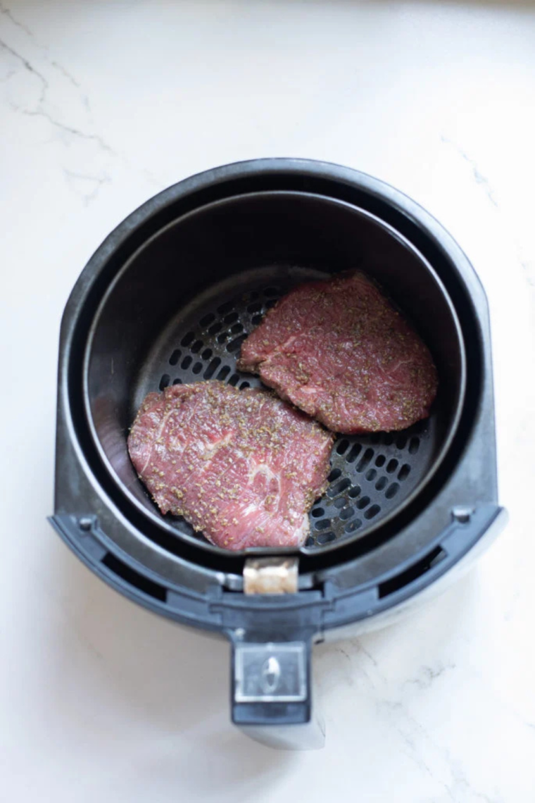 Preheating the air fryer to 400°F (200°C) and greasing the basket with parchment paper for cooking.