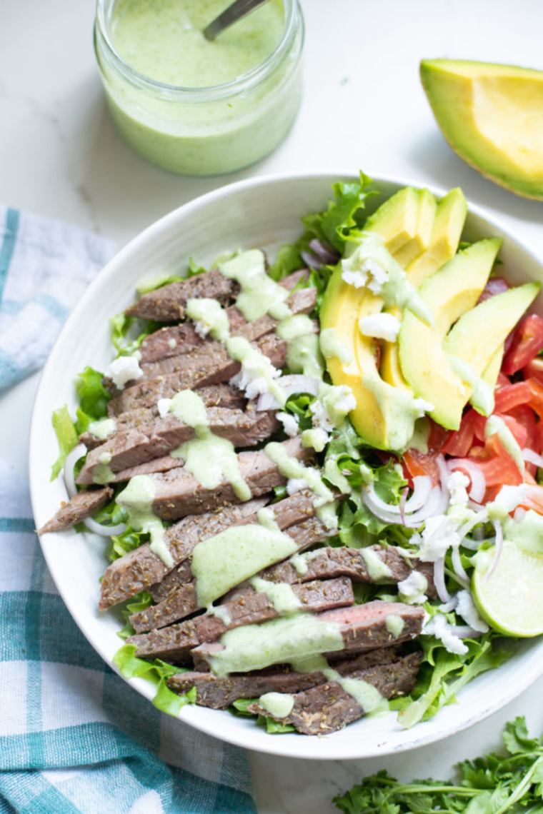 A vibrant and delicious air fryer steak salad served with fresh veggies and topped with homemade cilantro dressing.