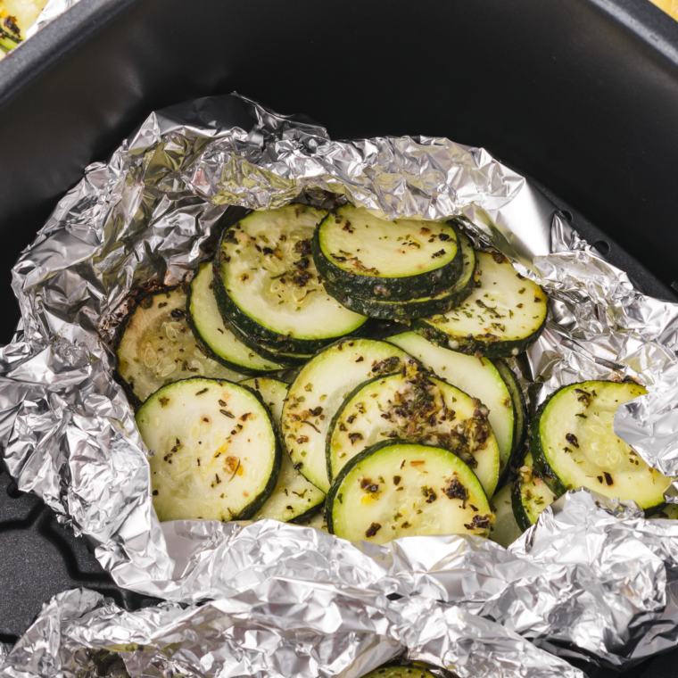 Freshly cooked zucchini foil packets in the air fryer, sprinkled with herbs.