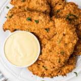 Jar of golden Carolina honey mustard BBQ sauce with a basting brush and fresh ingredients nearby.