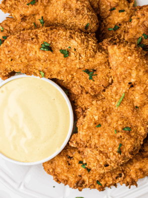 Jar of golden Carolina honey mustard BBQ sauce with a basting brush and fresh ingredients nearby.