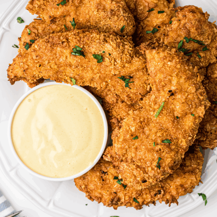 Jar of golden Carolina honey mustard BBQ sauce with a basting brush and fresh ingredients nearby.