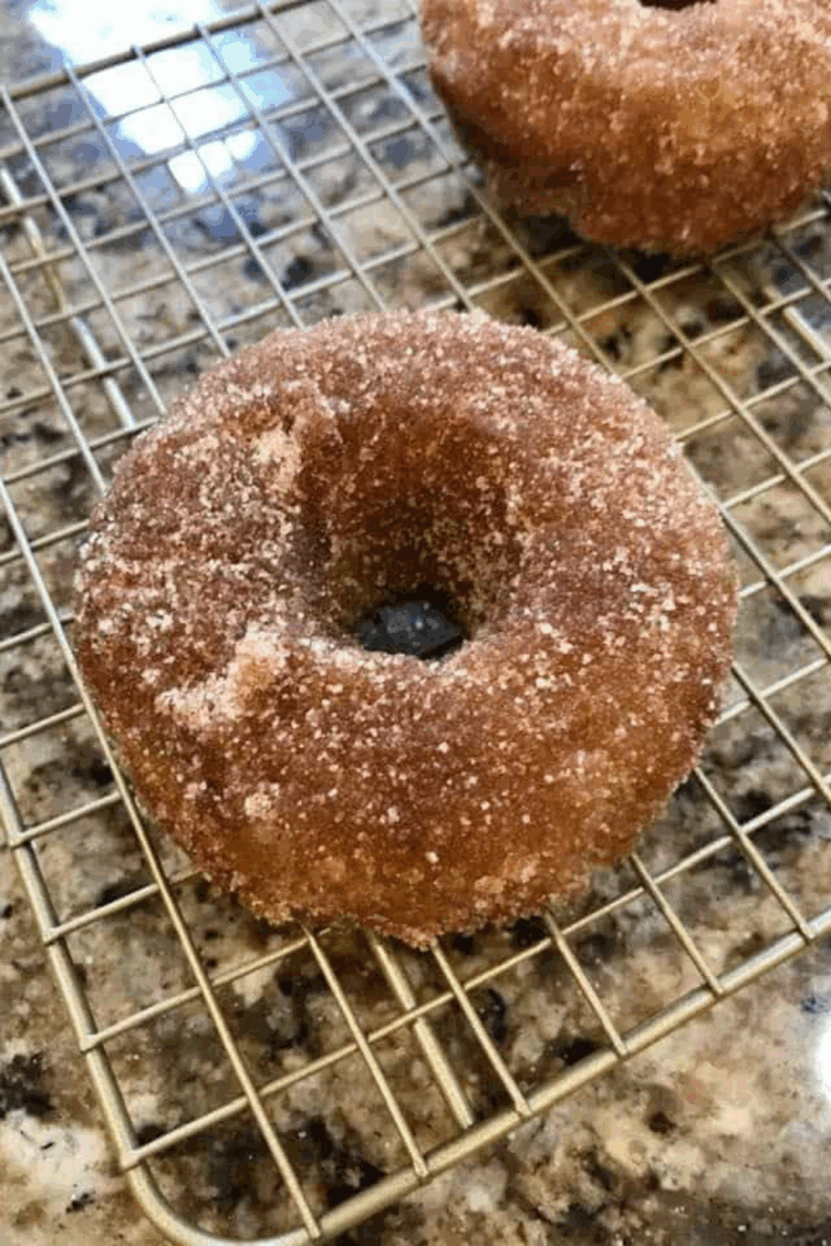 Golden apple cider donuts made in the air fryer, dusted with cinnamon sugar.