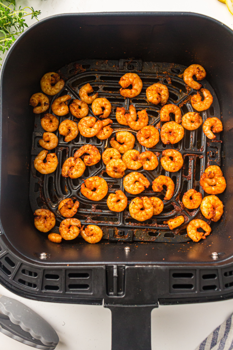 Shrimp placed in a single layer in the air fryer basket avoiding overlap to prevent steaming.