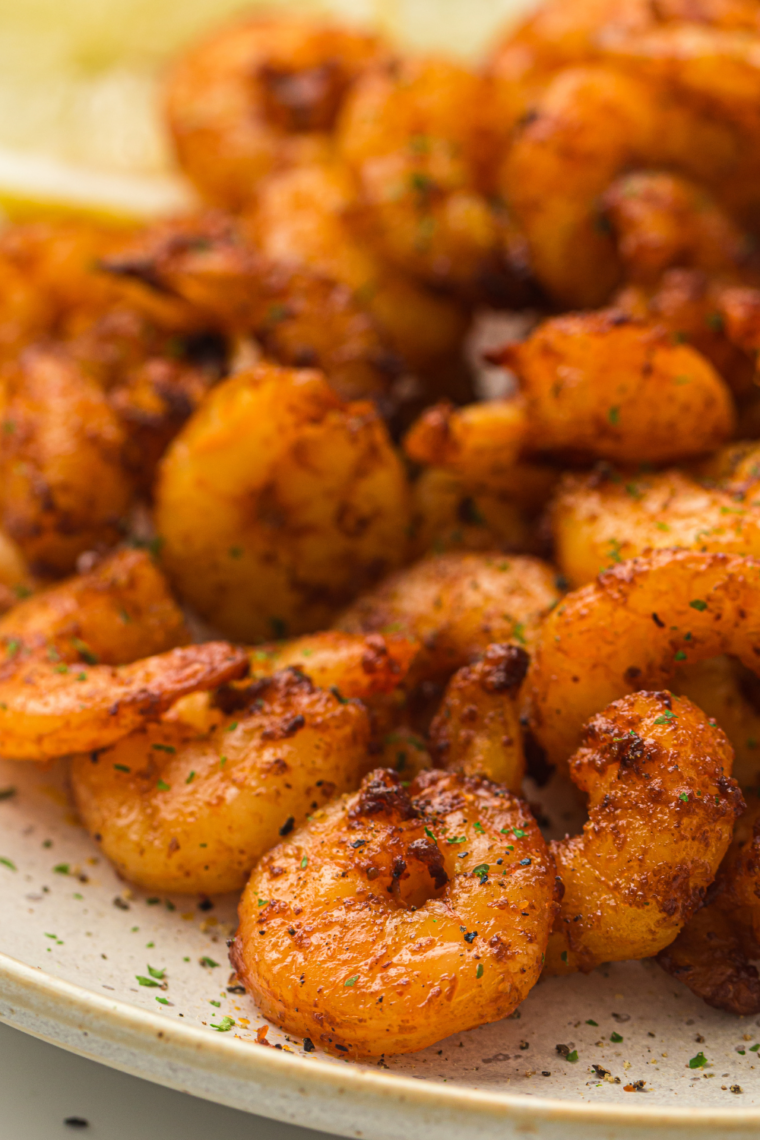 Juicy air fryer lemon garlic shrimp garnished with parsley and fresh lemon slices on a serving plate