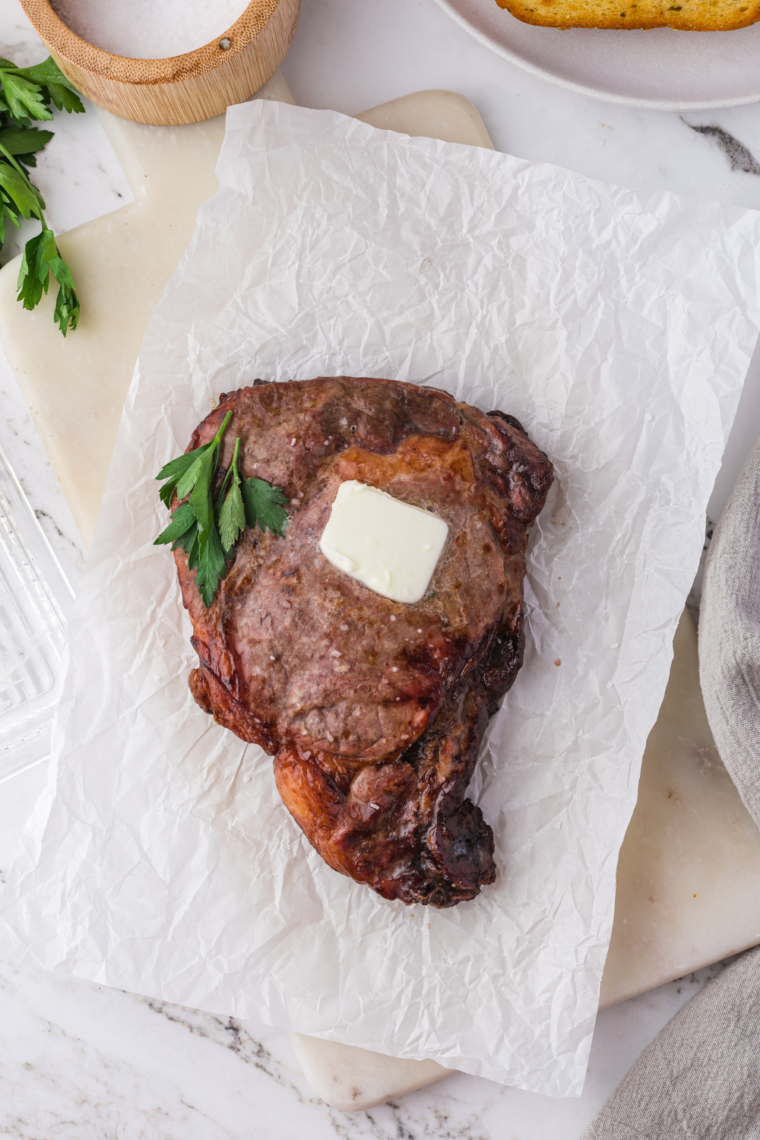 Frozen steak seasoned and placed in the air fryer basket, ready for cooking to perfection.