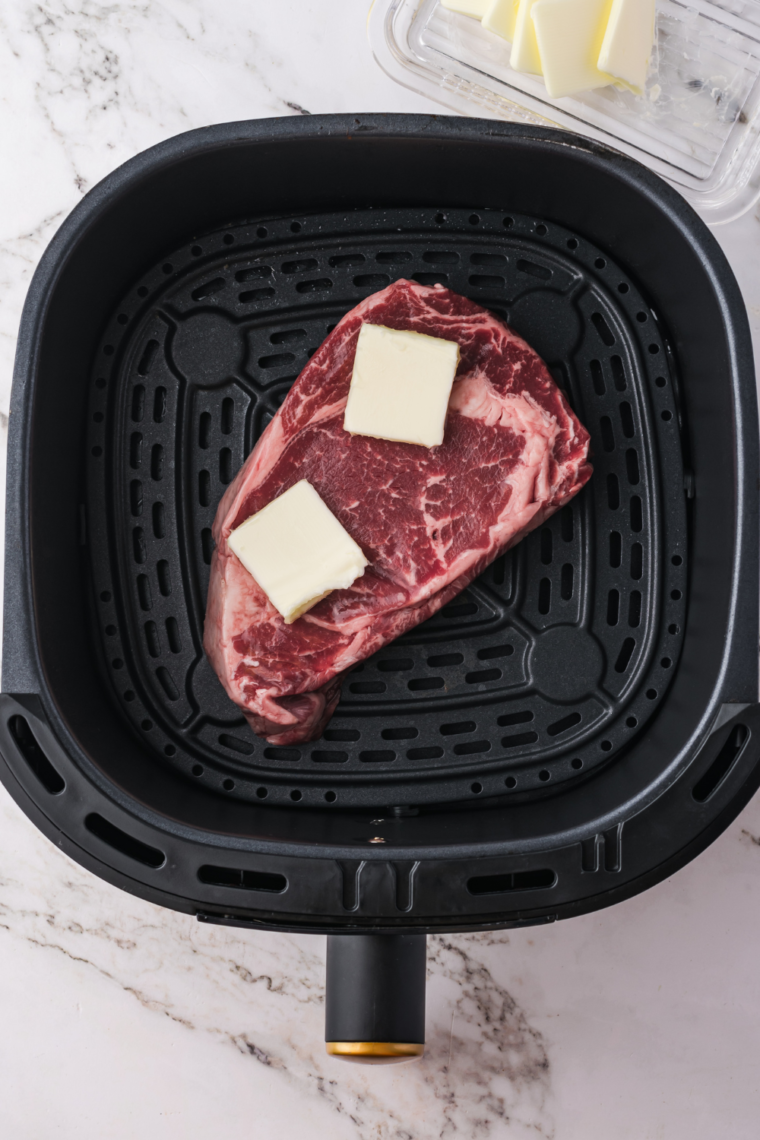 Frozen steak placed in the air fryer basket, air frying for 10-12 minutes with a flip halfway through