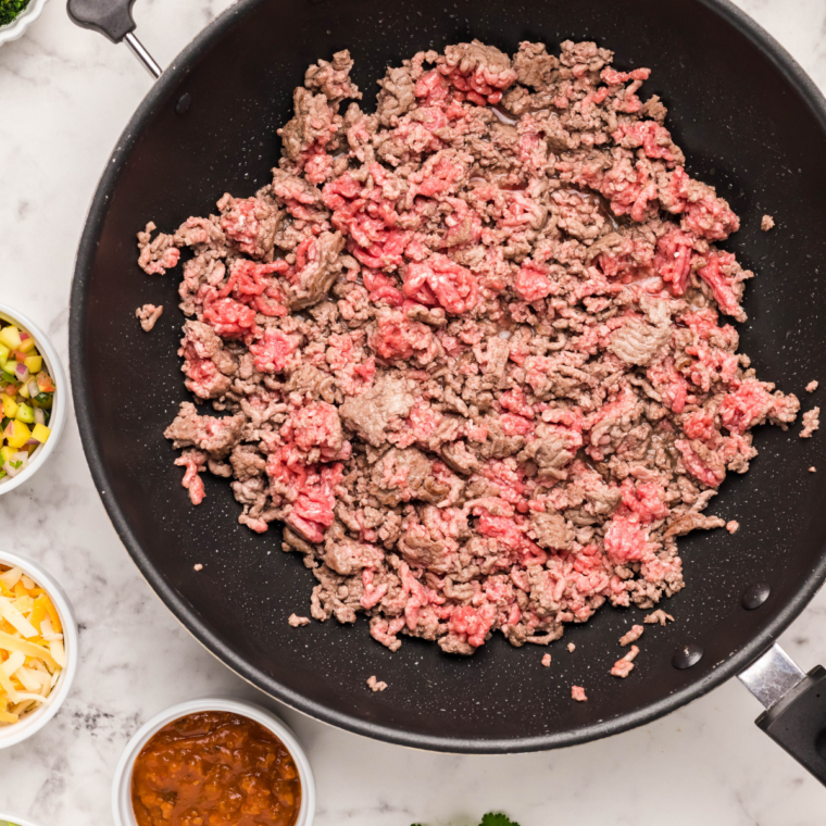 Ground beef browning in a skillet with homemade taco seasoning.