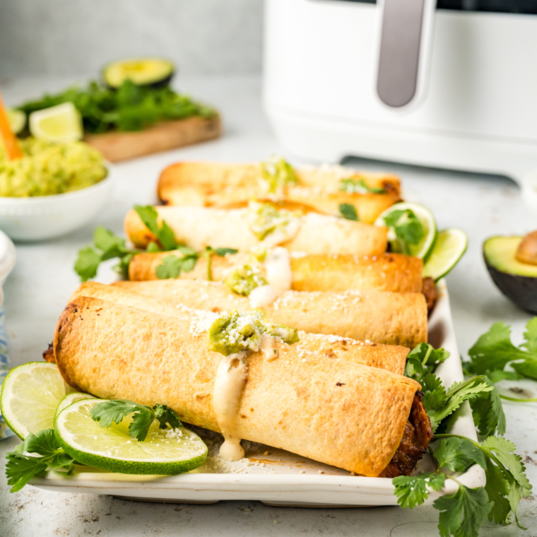 Plate of golden brown Air Fried Refried Bean and Veggie Flautas, ready to serve with dipping sauce.