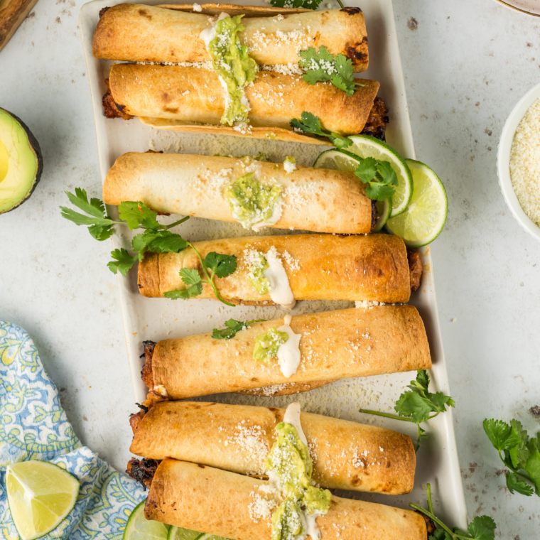 Air Fried Refried Bean and Veggie Flautas arranged on a white plate, garnished with fresh cilantro and served with salsa.