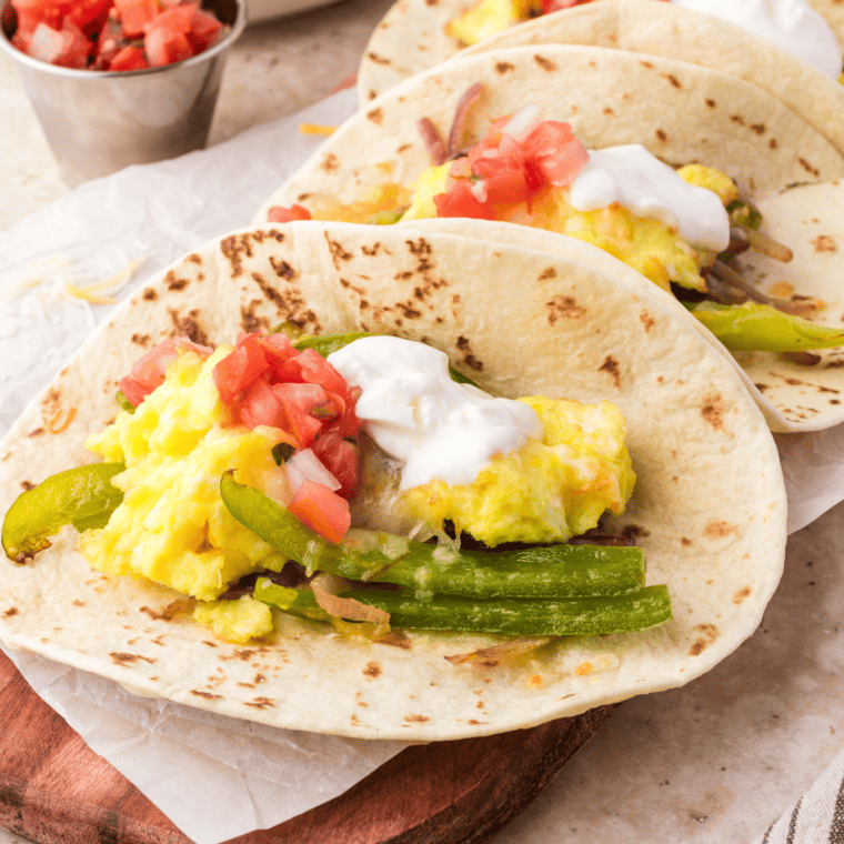 Crispy Air Fryer Breakfast Tacos filled with scrambled eggs, melted cheese, and fresh toppings, served on a white plate.