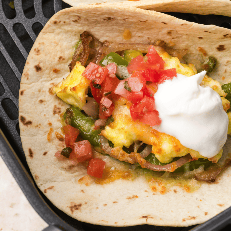 Top air fryer breakfast tacos with sour cream, diced tomatoes, and extra bell peppers for added flavor and enjoy!