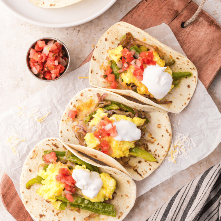 Air fryer breakfast tacos filled with scrambled eggs, sautéed vegetables, and melted cheese, topped with your favorite toppings.